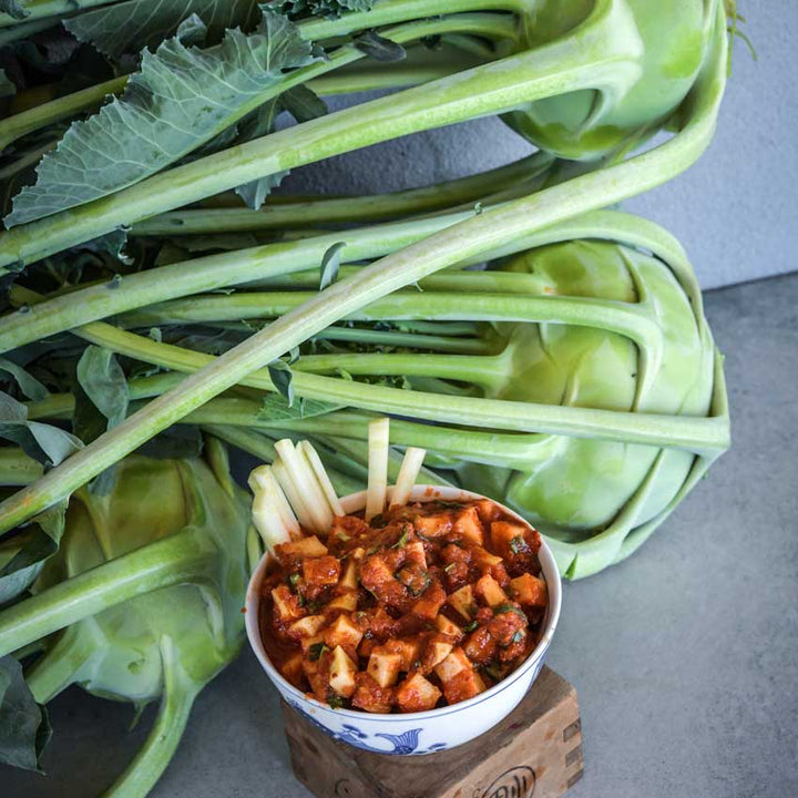 Delicacy White Kohlrabi behind a bowl of Kohlrabi kimchi in a decorative bowl.
