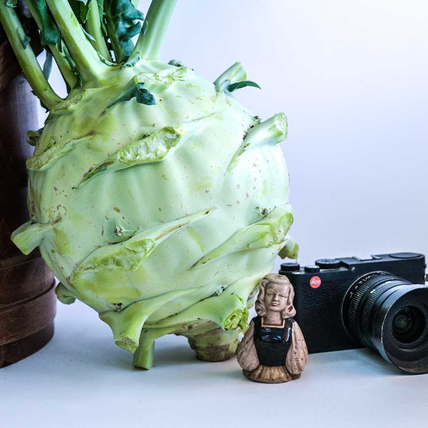 Superschmelz or Giant White Kohlrabi on a white background next to an old camera.