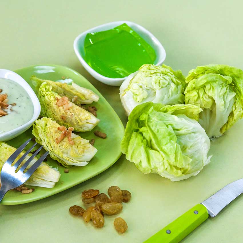 Tom Thumb Lettuce heads on table top next to a plate of quartered lettuce heads and a bowl of jello.