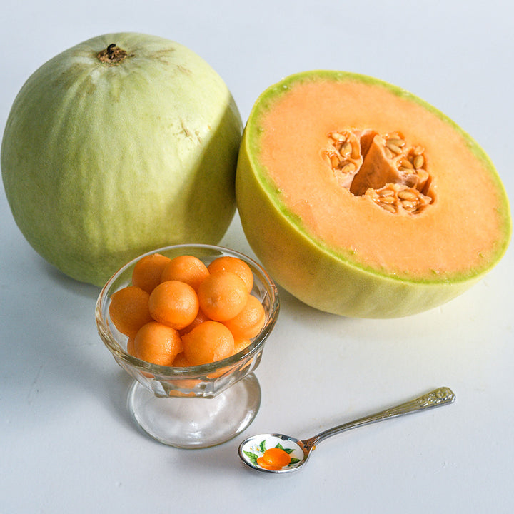 Honeydew Orange Flesh halved and an ice cream dish full of melon balls