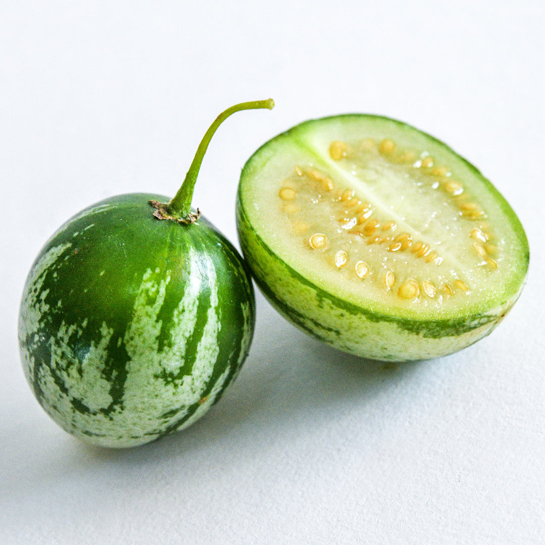 One whole and one half of Tzimbalo Melon Pears on a high key background.
