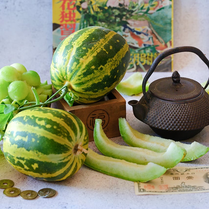 Japanese Tiger Melons with a Japanese teapot, coins, melon slices and melon balls on light background.