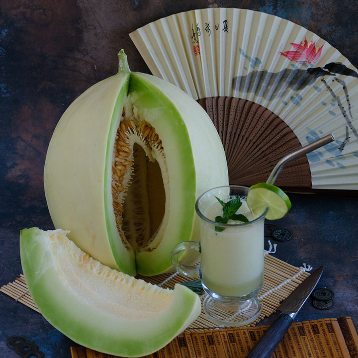 Whole and cut White Lanzhou Melon with Chinese accents on wooden background.