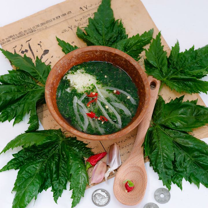 Oniyaya Molokhia recipe in a bowl with leaves surrounding it.