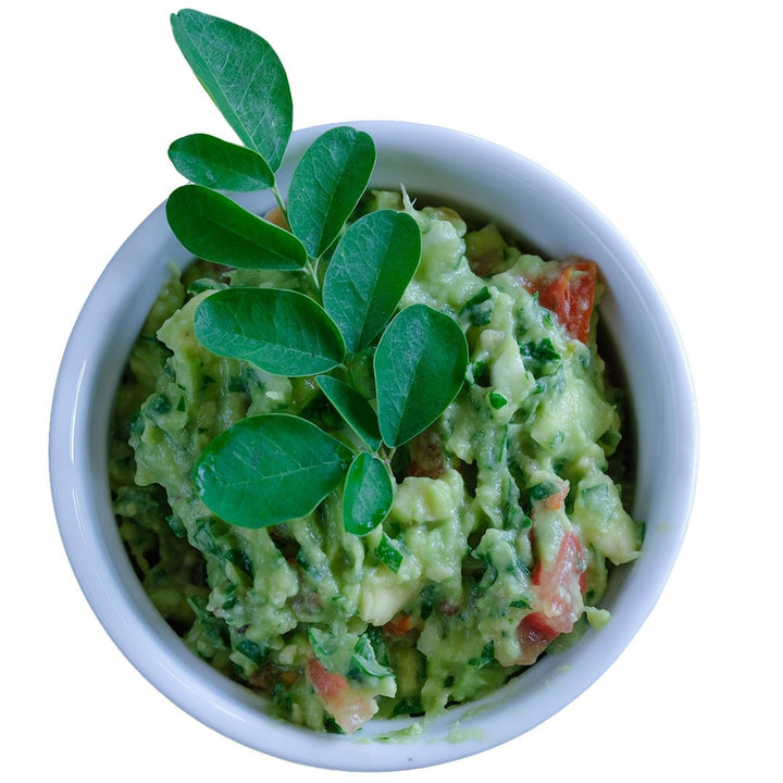 Dwarf Moringa leaves in a bowl of guacamole.