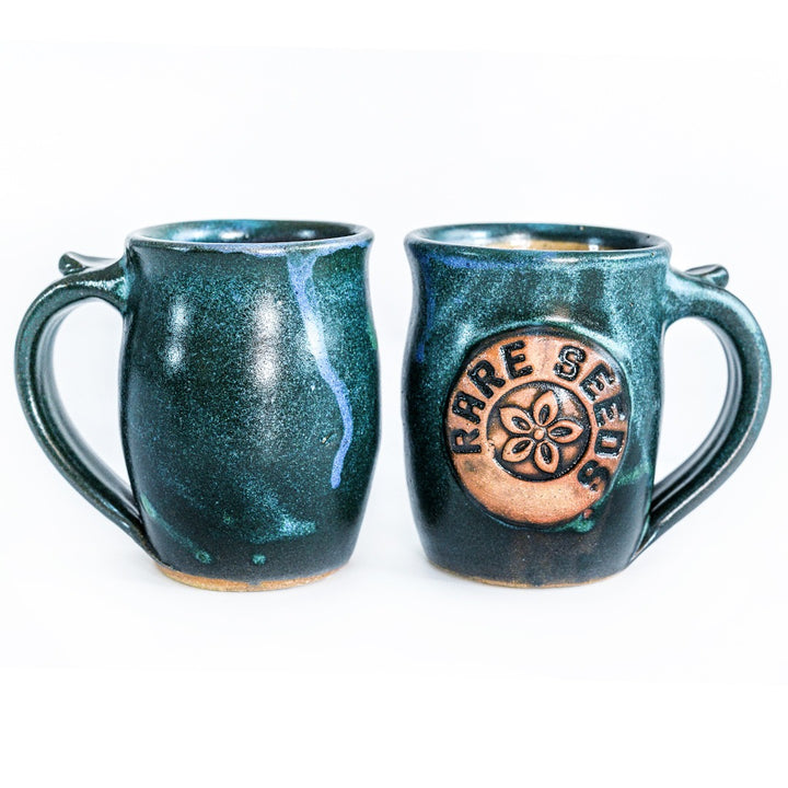 A couple of Handmade Green/Blue Stoneware Mugs with RareSeeds logo on a white background.