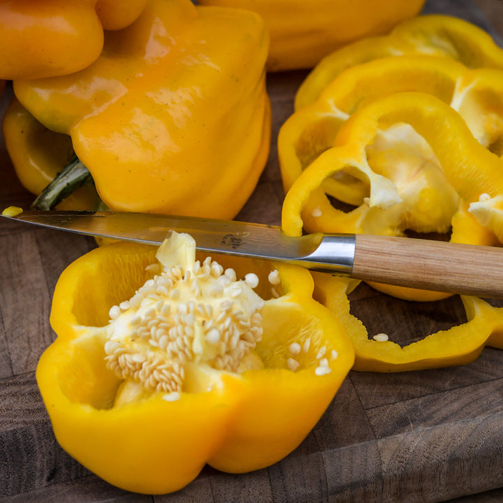 A close up of cut and whole Goldenmane Lion Sweet Peppers.