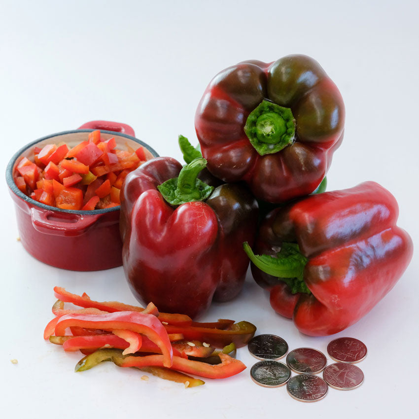 Three King of the North Sweet Peppers and a bowl of diced pepper, next to long pepper slices and coins on a white background.