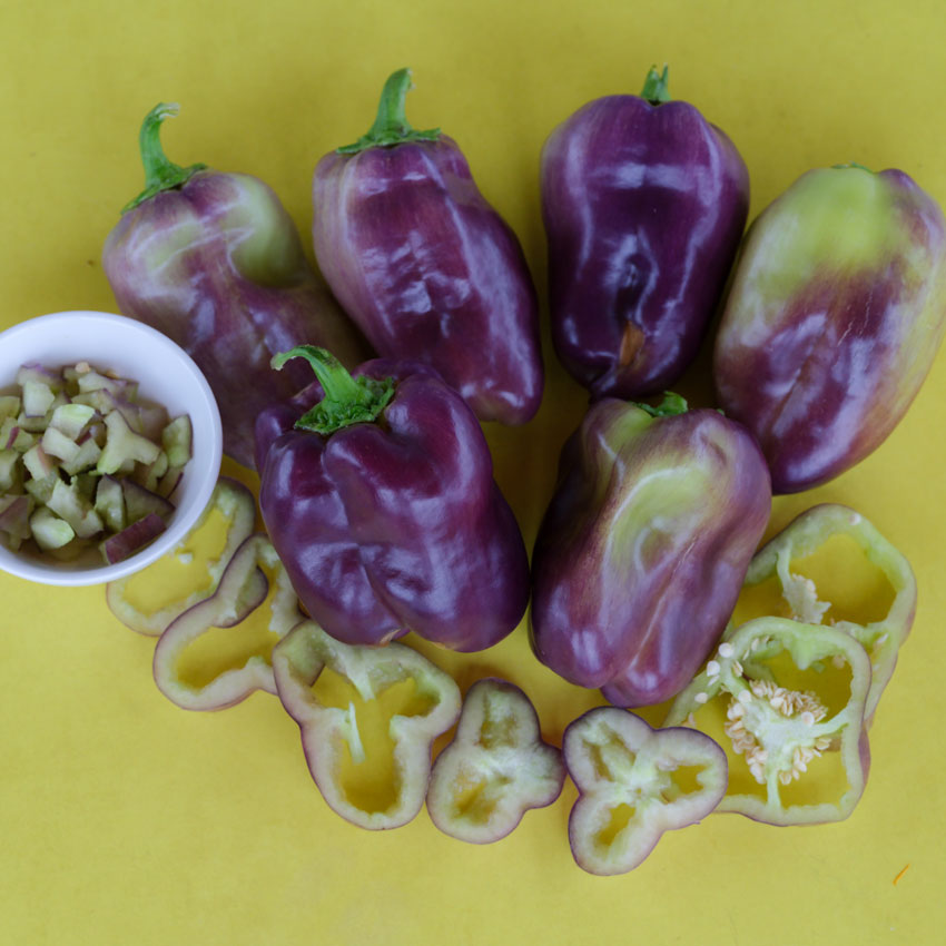 Six Blot Sweet Peppers with purple to light green shades. Diced pepper in a small bowl next to slices.