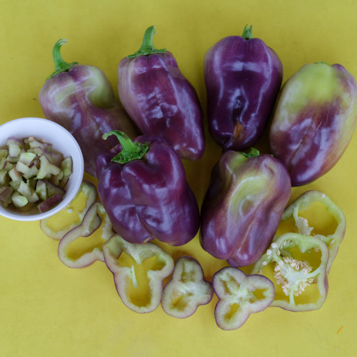 Six Blot Sweet Peppers with purple to light green shades. Diced pepper in a small bowl next to slices.