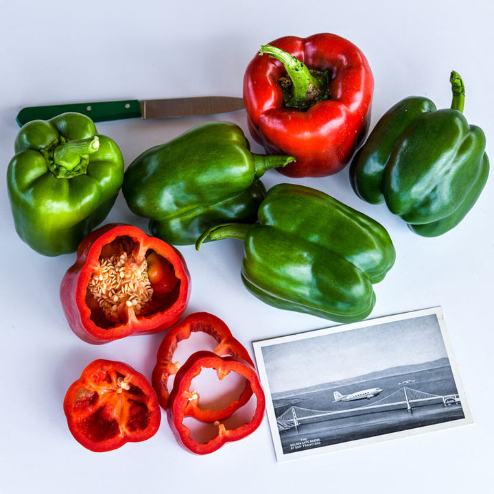 Several California Wonder Sweet Peppers some green and red on a white background.