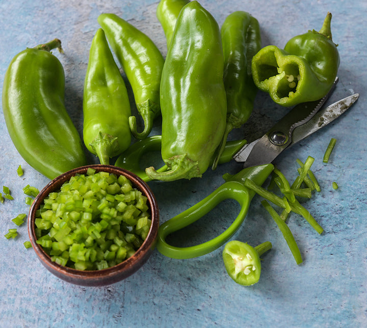 Anaheim Peppers, julienned and diced on blue background.