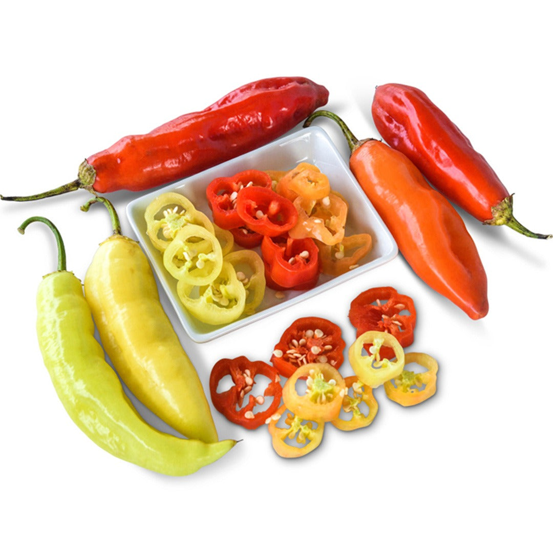 Whole Aji Cristal Hot Peppers next to a white bowl of hot pepper slices on a white background.