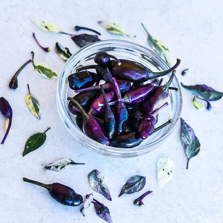 Jigsaw Peppers in clear bowl on lightly marbled background.