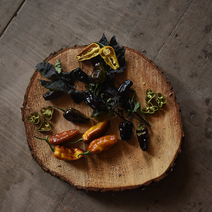 Puma Peppers and slices on wooden plank.