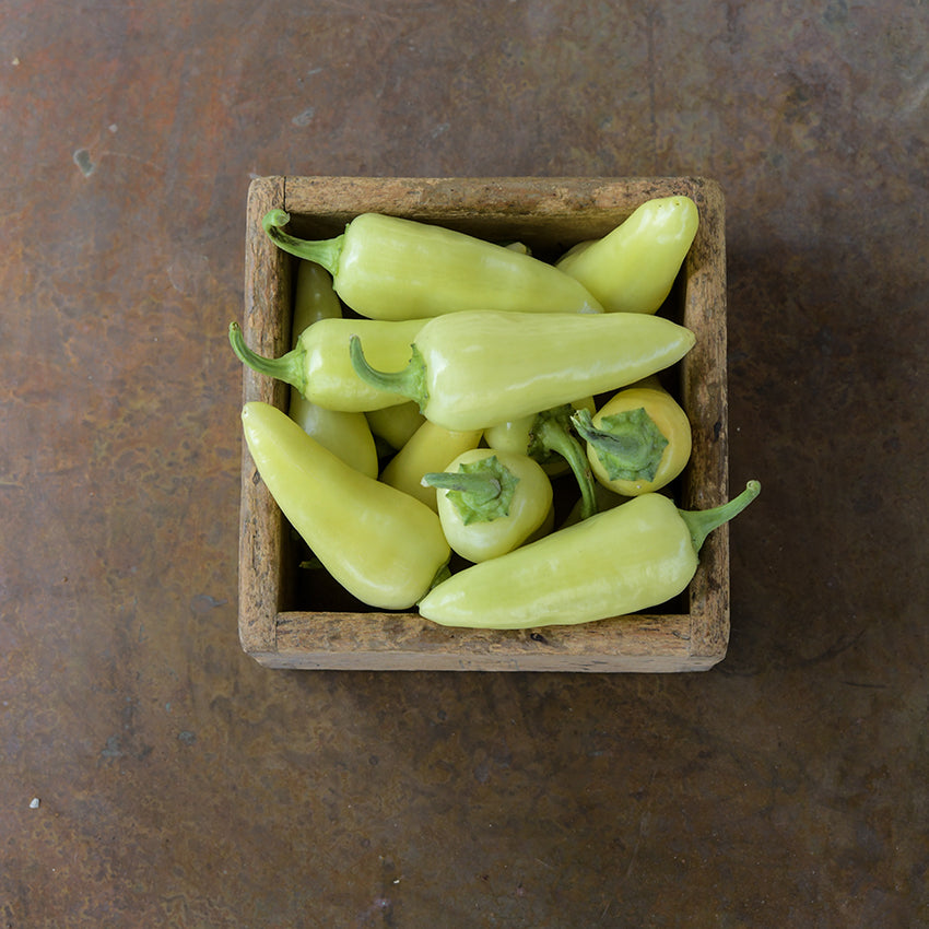 Greenish Santa Fe Grande Peppers in wooden box.