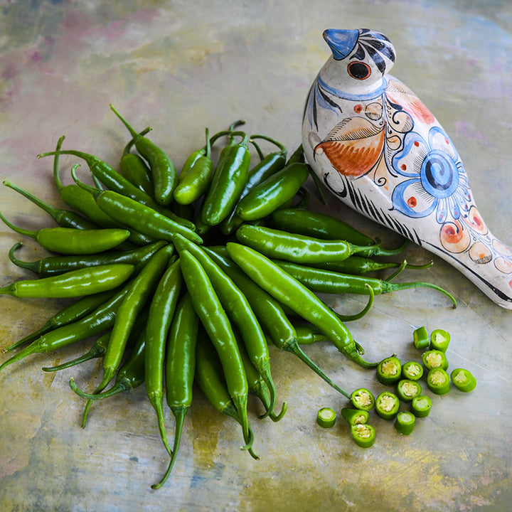 Serrano Tampiqueno Peppers with bird figurine on marble countertop.
