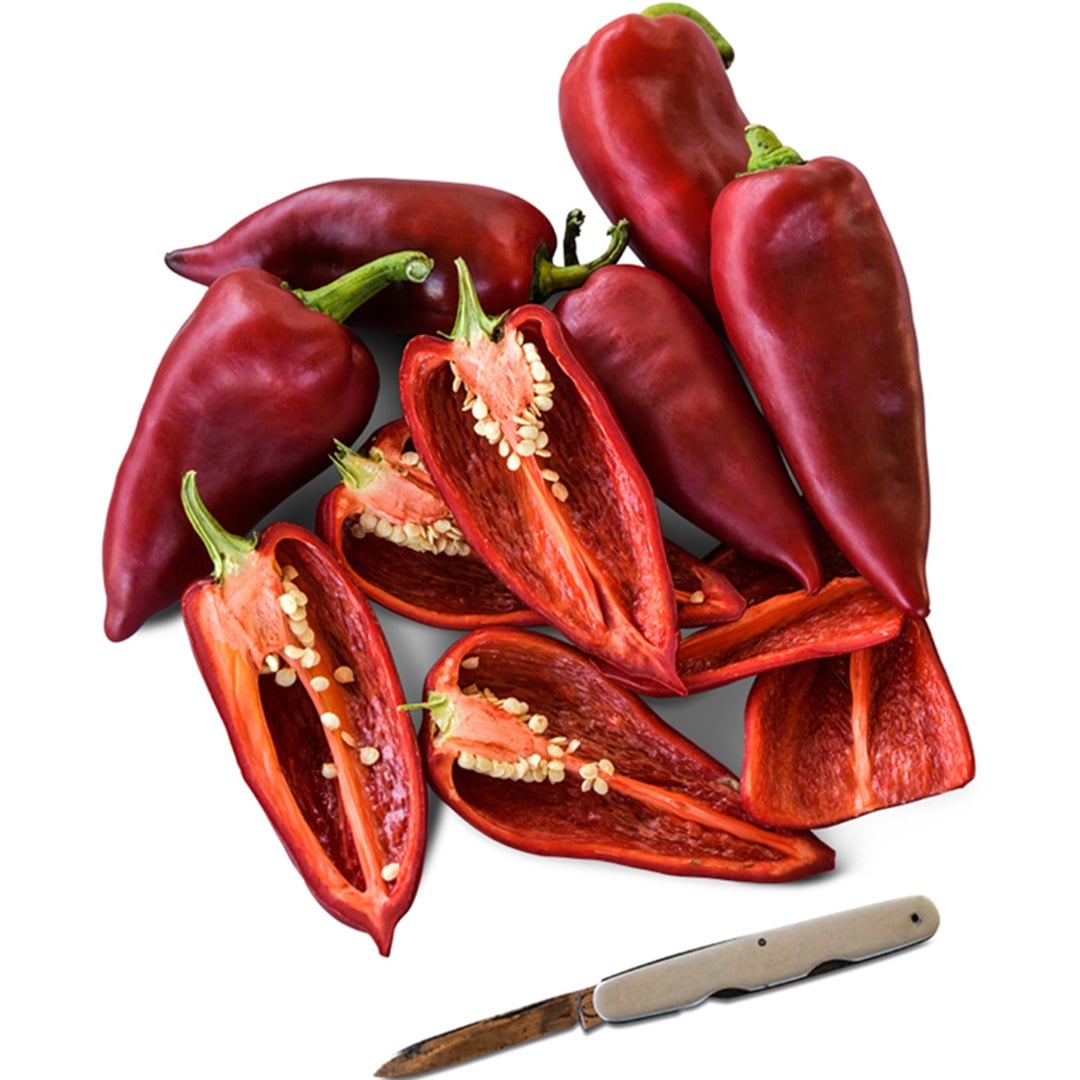 Sliced and whole Ajvarski Sweet Peppers on a white background.