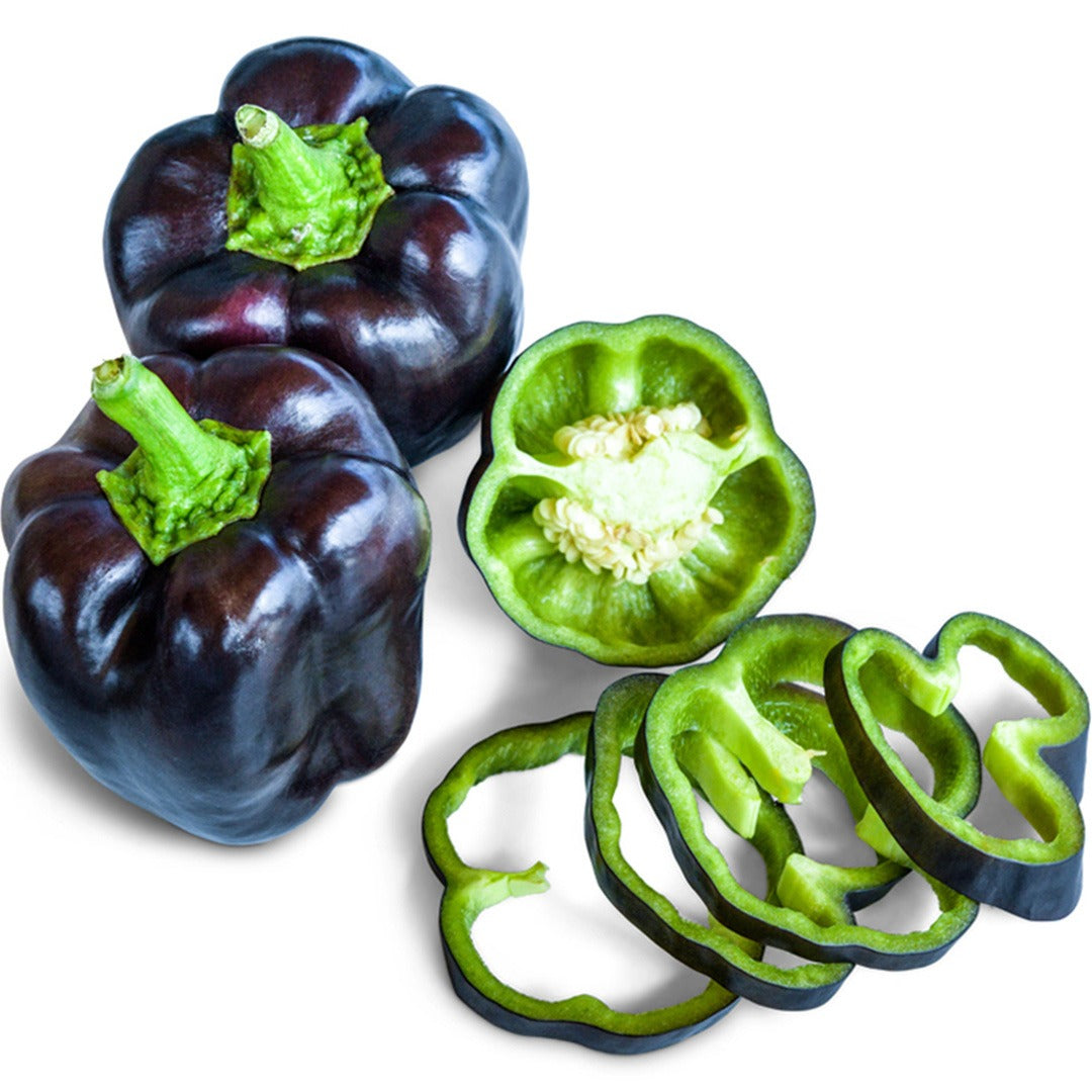 Two Purple Beauty Sweet Peppers next to slices on a white background.