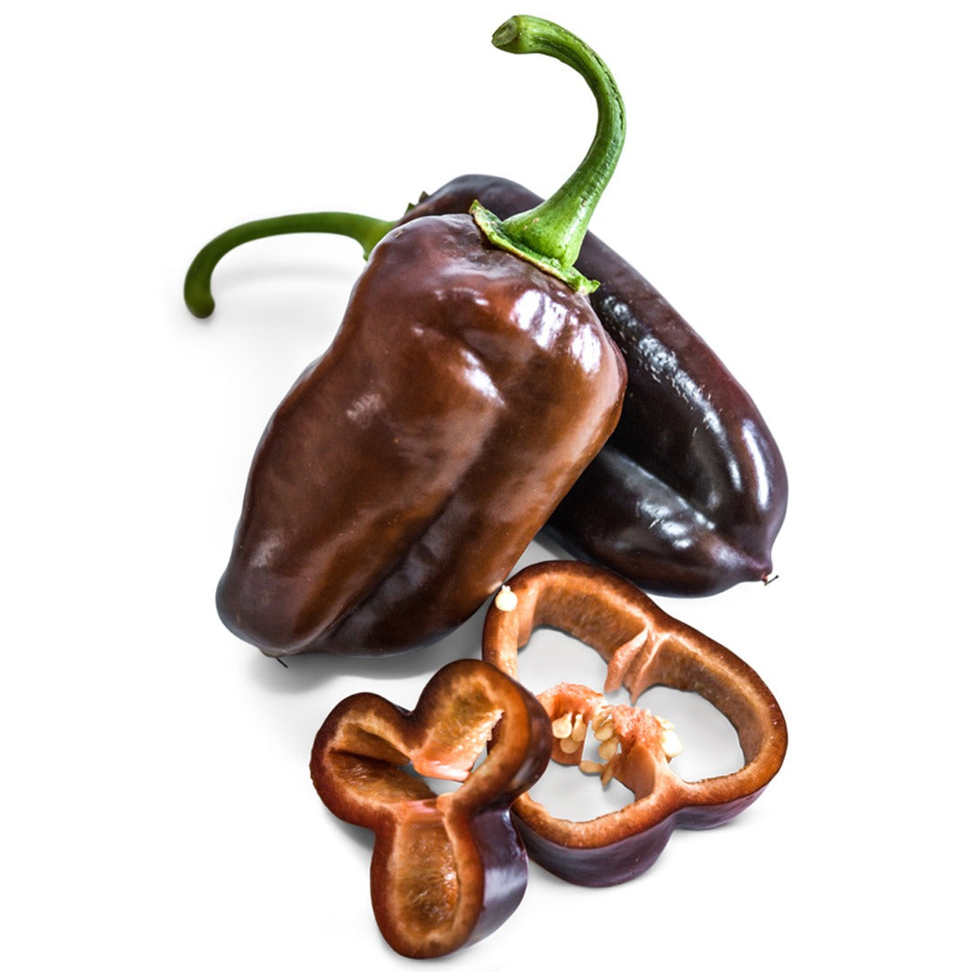 Two whole Sweet Chocolate Sweet Peppers next to slices on a white background.