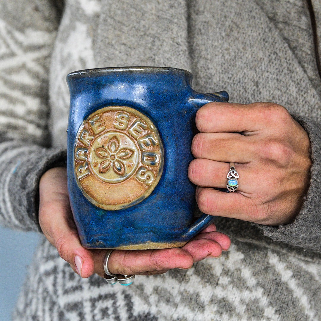 Woman holding a Handmade Local Mug Blue/Grey Pottery with a sweater on.