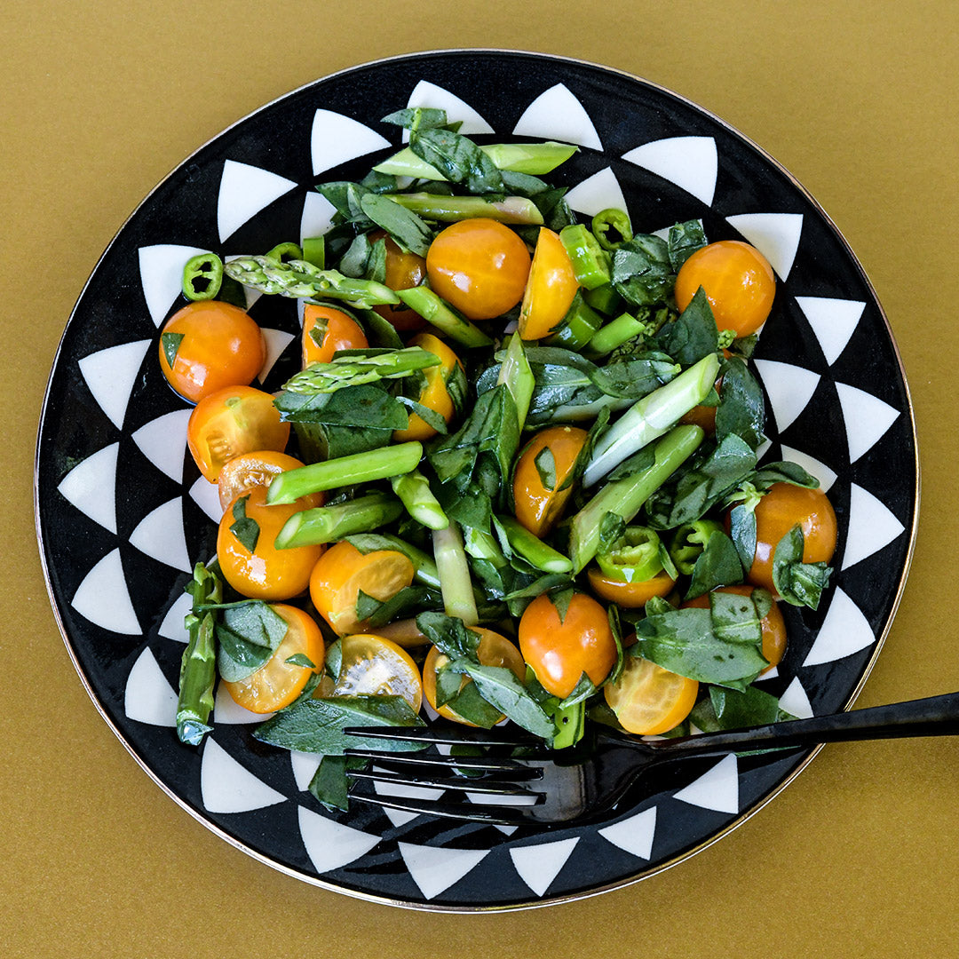 Mary Washington Asparagus In a black and white bowl on a gold background.