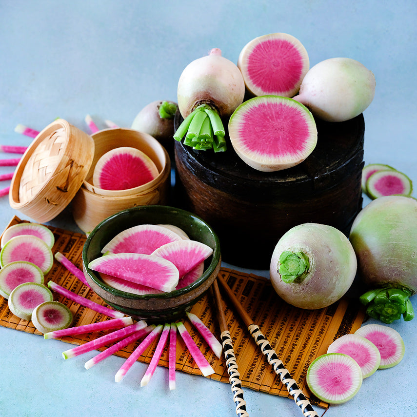 Whole and sliced Chinese Red Meat Radishes arranged on light blue background.