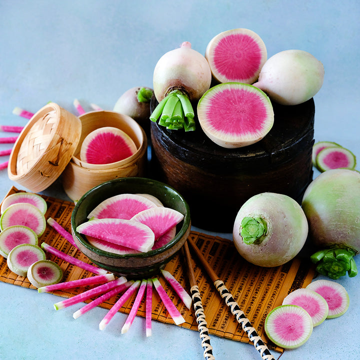 Whole and sliced Chinese Red Meat Radishes arranged on light blue background.