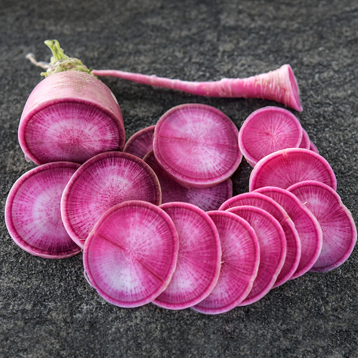 Sliced Pusa Gulabi Radish on a stone background.