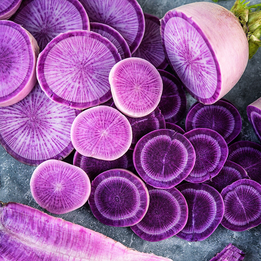 A close-up of cut Pusa Jamuni Radishes on a concrete background.