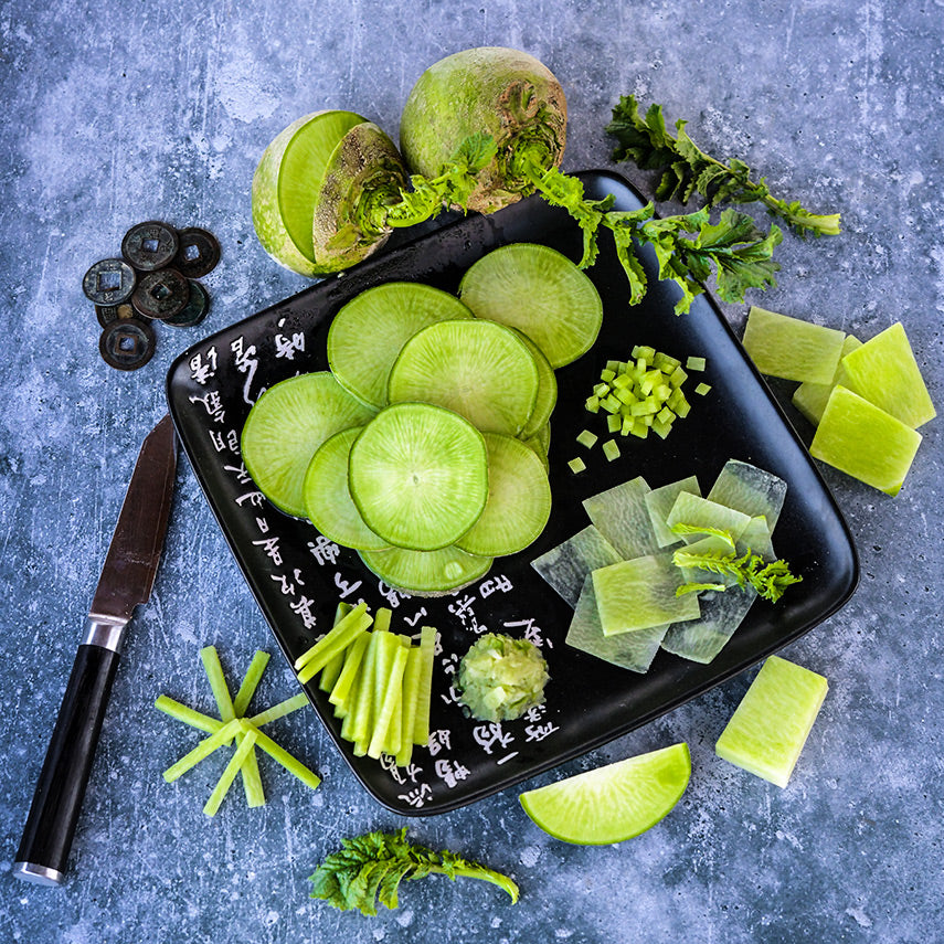 Cut and whole Wasabi Radish arranged around a plate on a gray background.