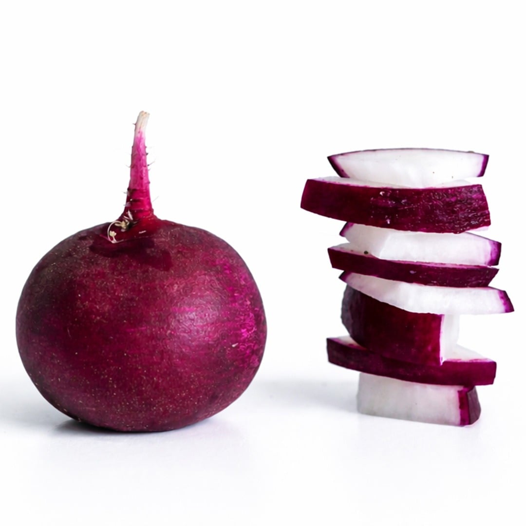 Malaga radish next to stacked slices of radishes against a white background.