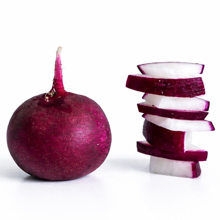 Malaga radish next to stacked slices of radishes against a white background.