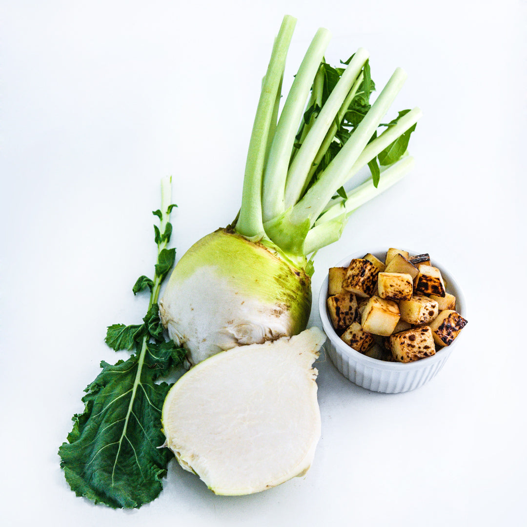 A whole and sliced Macomber Turnip Rutabaga with a bowl full of roasted rutabaga on white.