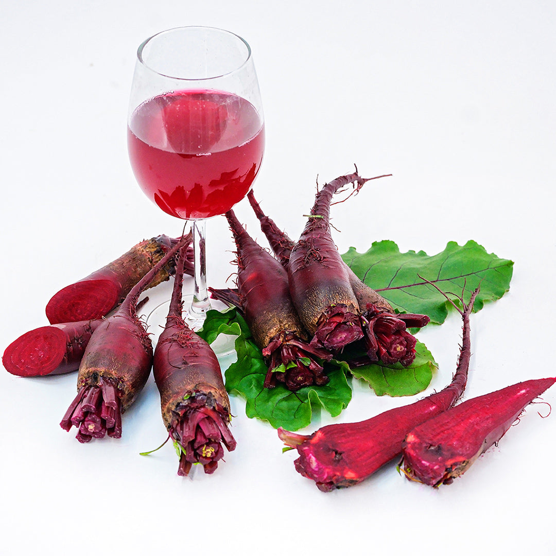 Renova Beets arranged around a glass of beet juice on a white background.