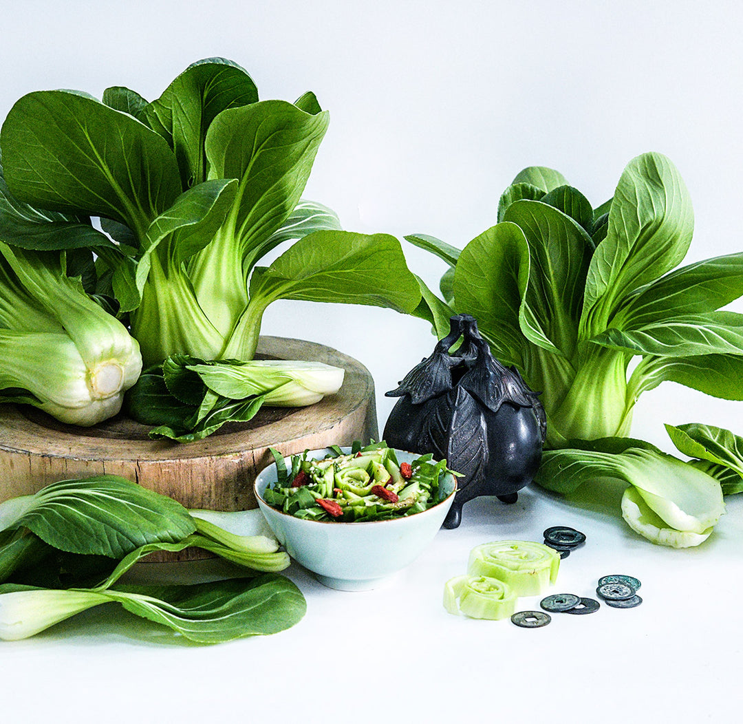 Fresh heads of Suzhou Baby Bok Choy with a bok choy salad on a white background.