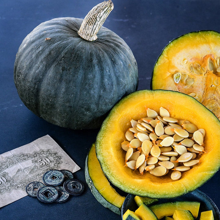 Whole and cut Tokyo Blue Winter Squash with seeds on dark blue background.