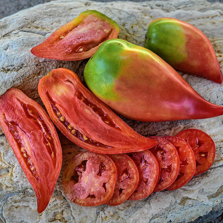 Cut and whole Korean Long Tomatoes on a stone background.