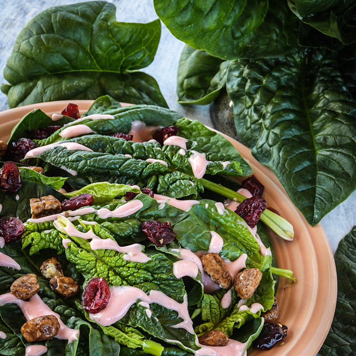 A salad made of Bloomsdale Long Standing Spinach surrounded by leaves on a light background.