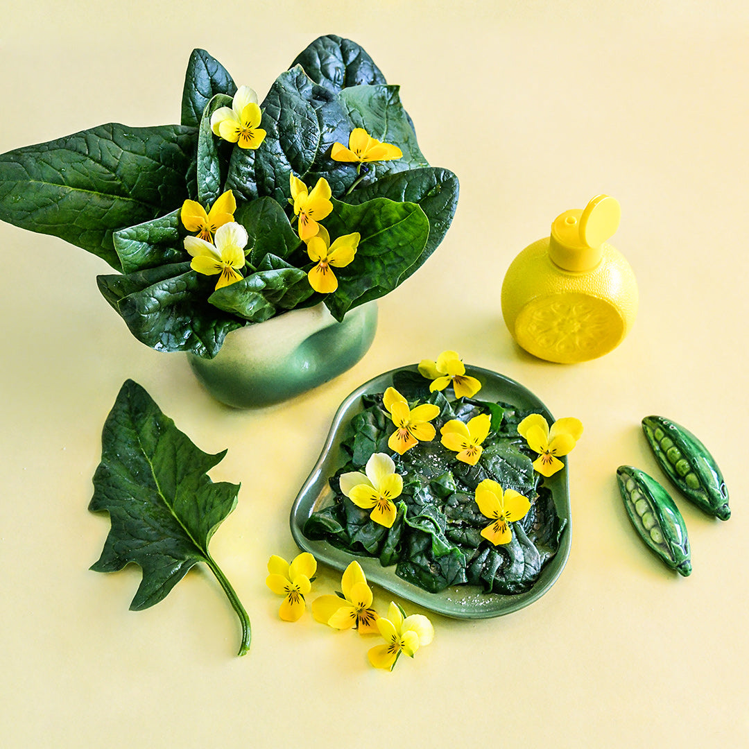 Cooked and raw Monnopa Spinach arranged on a yellow background.