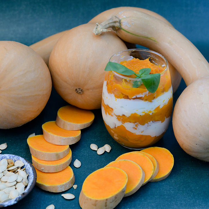 Cut and whole Canada Crookneck Winter Squash with a dessert recipe on a dark blue background.