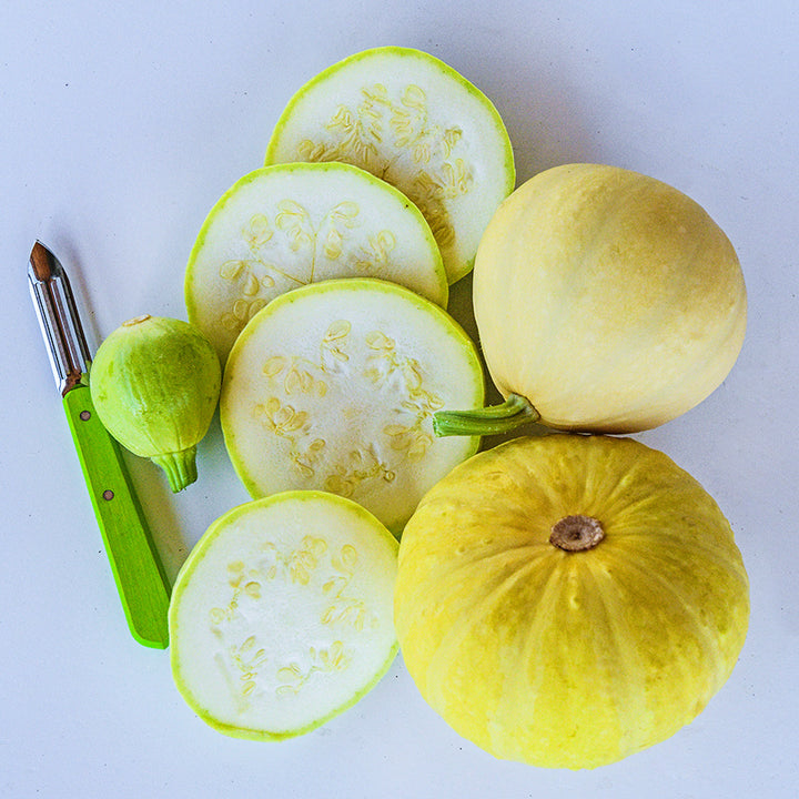 Whole and sliced Desi Summer Squash with a green handled knife on white background.