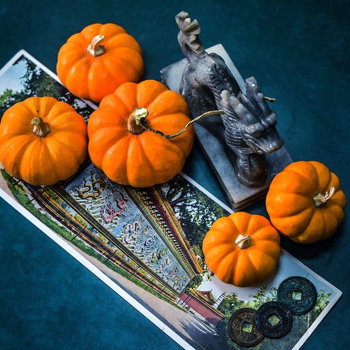 Jack Be Little Pumpkins with a stone dragon, postcard and coins on a jade background.