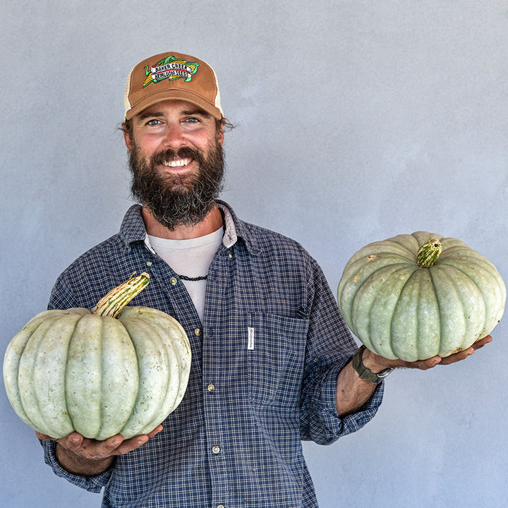 A Baker Creek employee happily holds Jarrahdale Pumpkin Winter Squash grown on the farm.