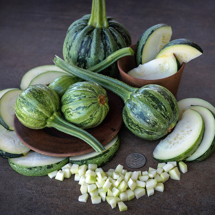 Kamo Kamo Summer Squash with slices and cubes and coin on dark background.