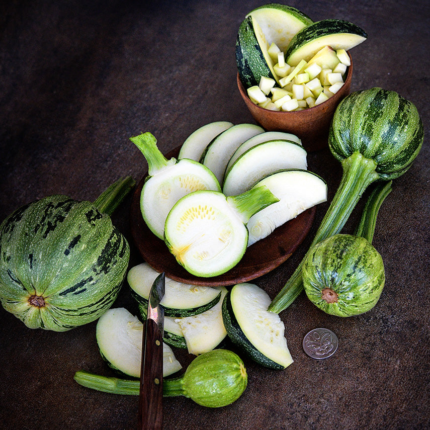 Whole and cut Kamo Kamo Summer Squash on a dark brown background.