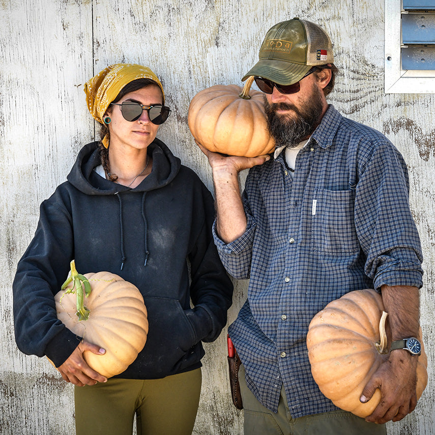 A couple of Baker Creek Garden crew employees holding Long Island Cheese Pumpkins.
