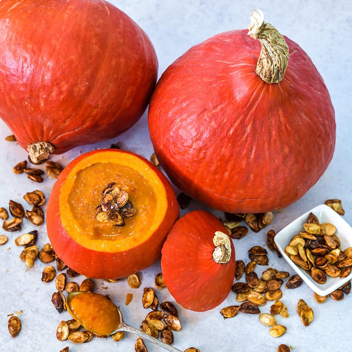 Whole and cut Red Kuri (Hokkaido) Winter Squash with soup served in a squash surrounded by seeds.
