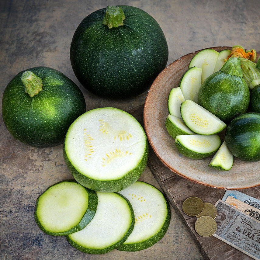 Cut and whole Tondo Scuro Di Piacenza Summer Squash on a rustic plate with Italian money.