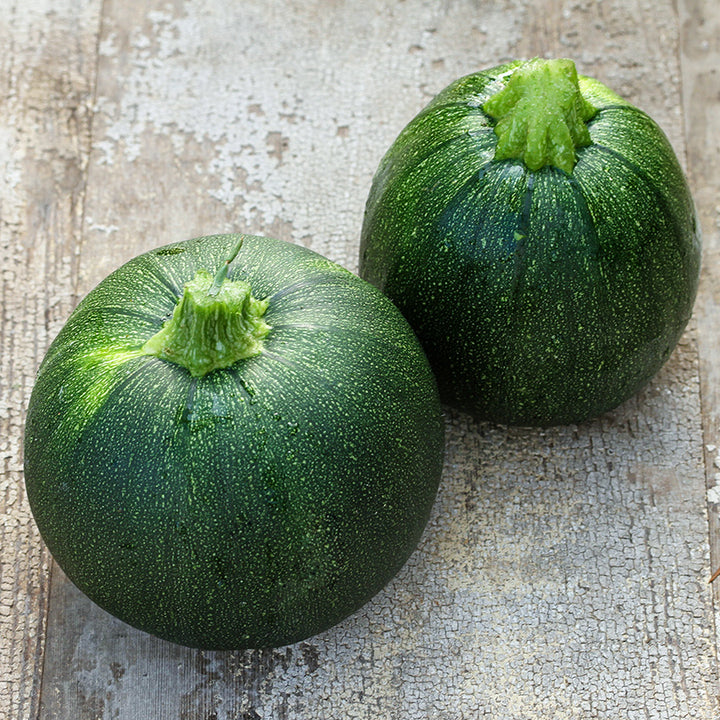 A couple of Tondo Scuro Di Piacenza Summer Squash on a weathered wood background.